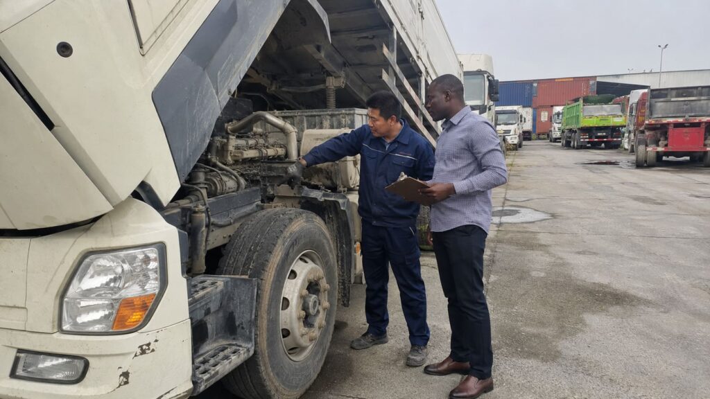 African buyer inspecting a used truck with a Chinese technician before import