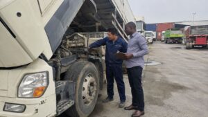 African buyer inspecting a used truck with a Chinese technician before import