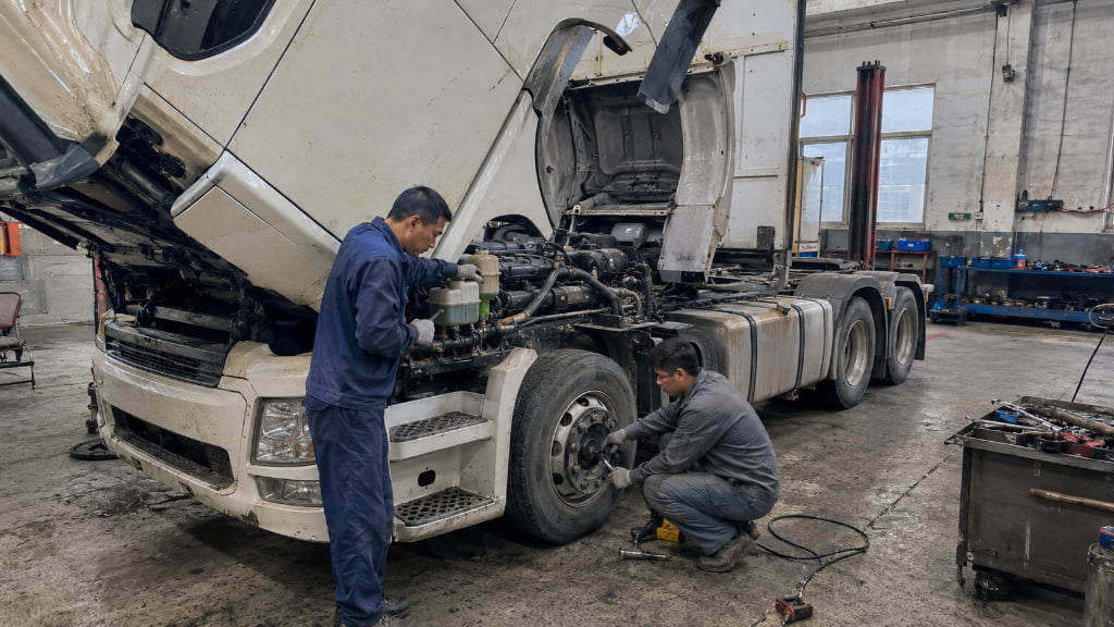 Chinese mechanics maintaining a used heavy truck in a repair workshop