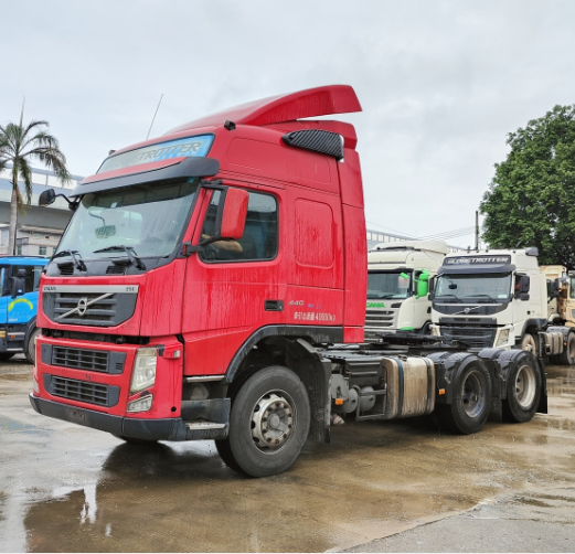 Second-hand tractor truck FM440 6x2 red for VOLVO high performance truck on hot sale, 440HP heavy duty red tractor, left front side view outdoor yard scene
