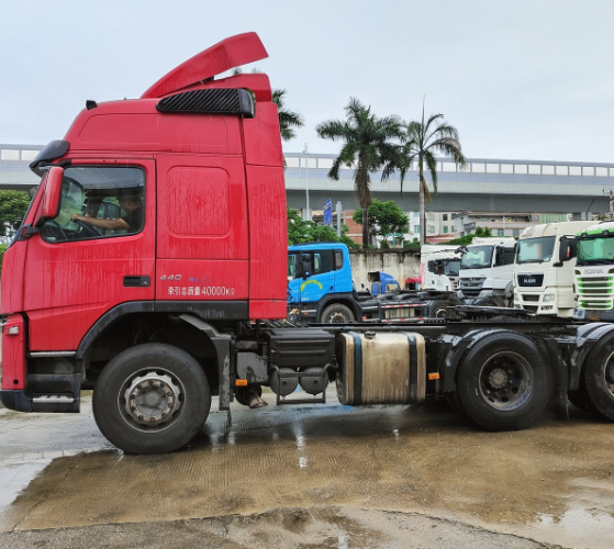 Second-hand tractor truck FM440 6x2 red for VOLVO high performance truck on hot sale, 440HP heavy duty red tractor, right front side view outdoor parking lot