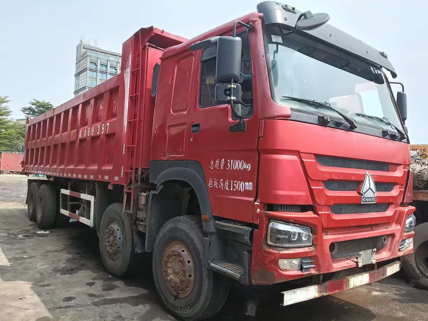 Side view of a used red Sinotruk HOWO dump truck