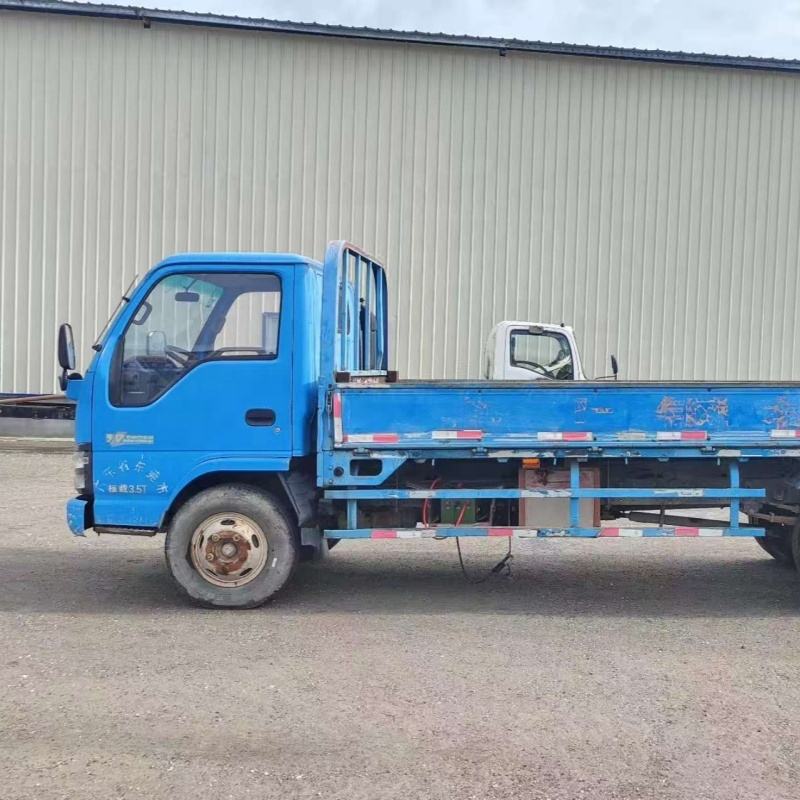 Outdoor front right side view of blue used Isuzu 700P 4x2 diesel flatbed cargo truck