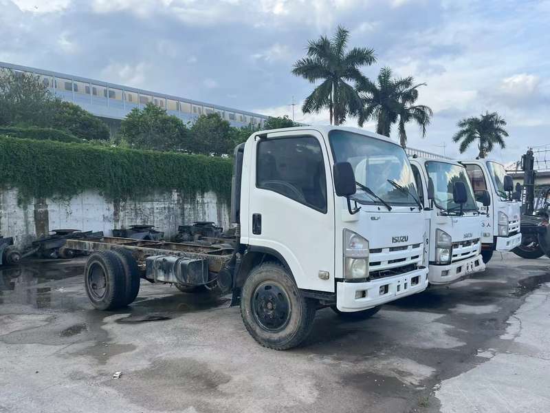 - Front right side view of multiple used white ISUZU 700P 4x2 light cargo trucks in stock yard
